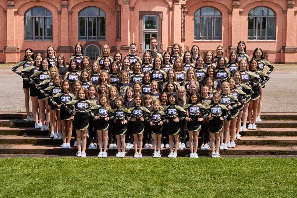 Gruppenfoto von Cheerleadern in einheitlichen Outfits vor einem historischen Gebäude.
